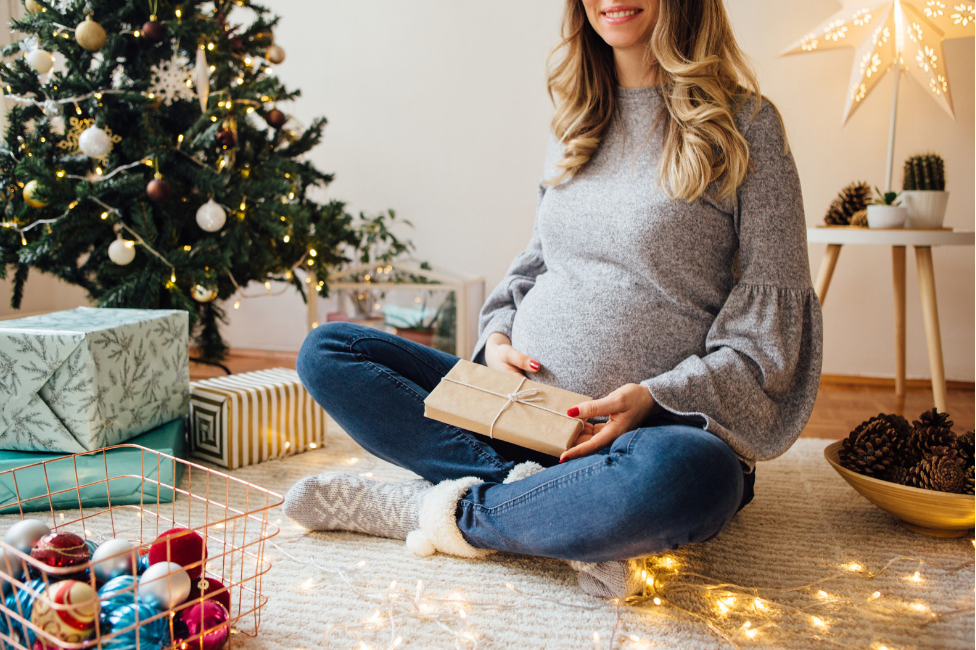 pregnant woman wrapping gifts during a christmas tree, why buying a new home during the holidays is the right time to buy