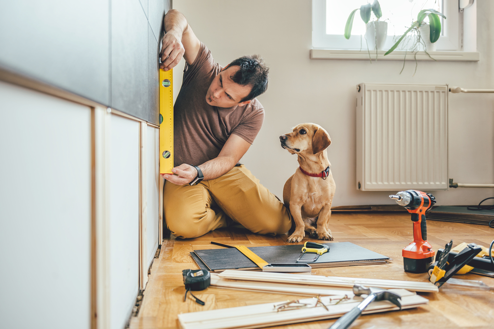 man doing repairs while his dog is watching
