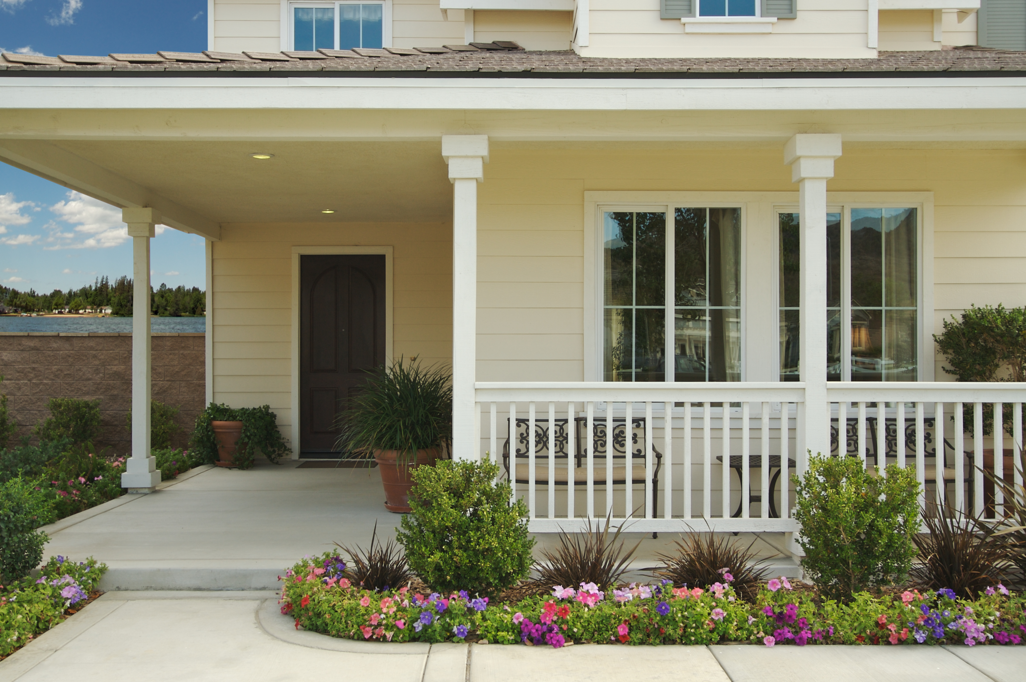 Welcoming home exterior with a covered porch, white railing, and vibrant flower beds signaling springtime curb appeal.