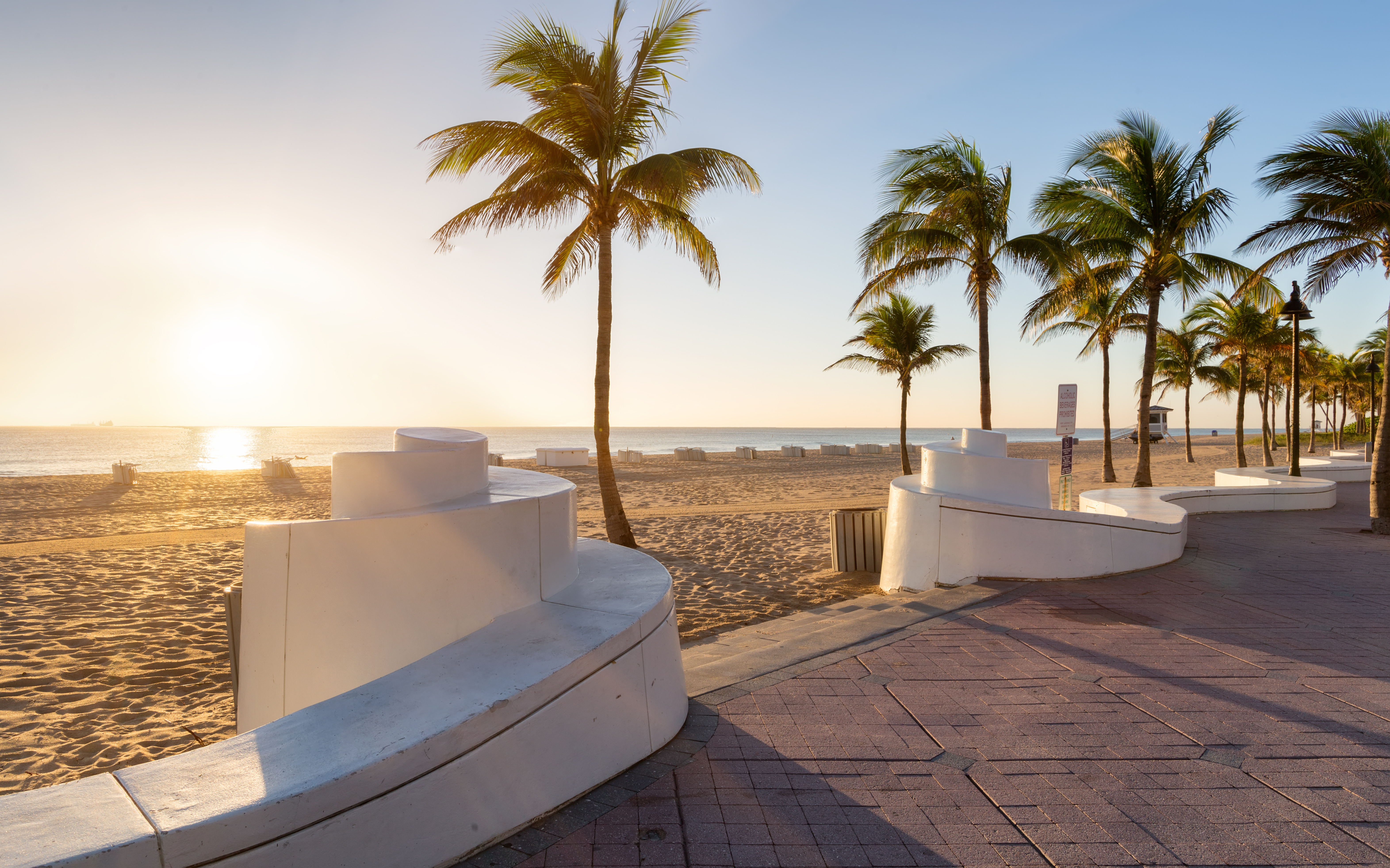 Scenic beach view in Fort Lauderdale, Florida with palm trees, blue ocean, and sunny skies—ideal setting for a vacation home investment