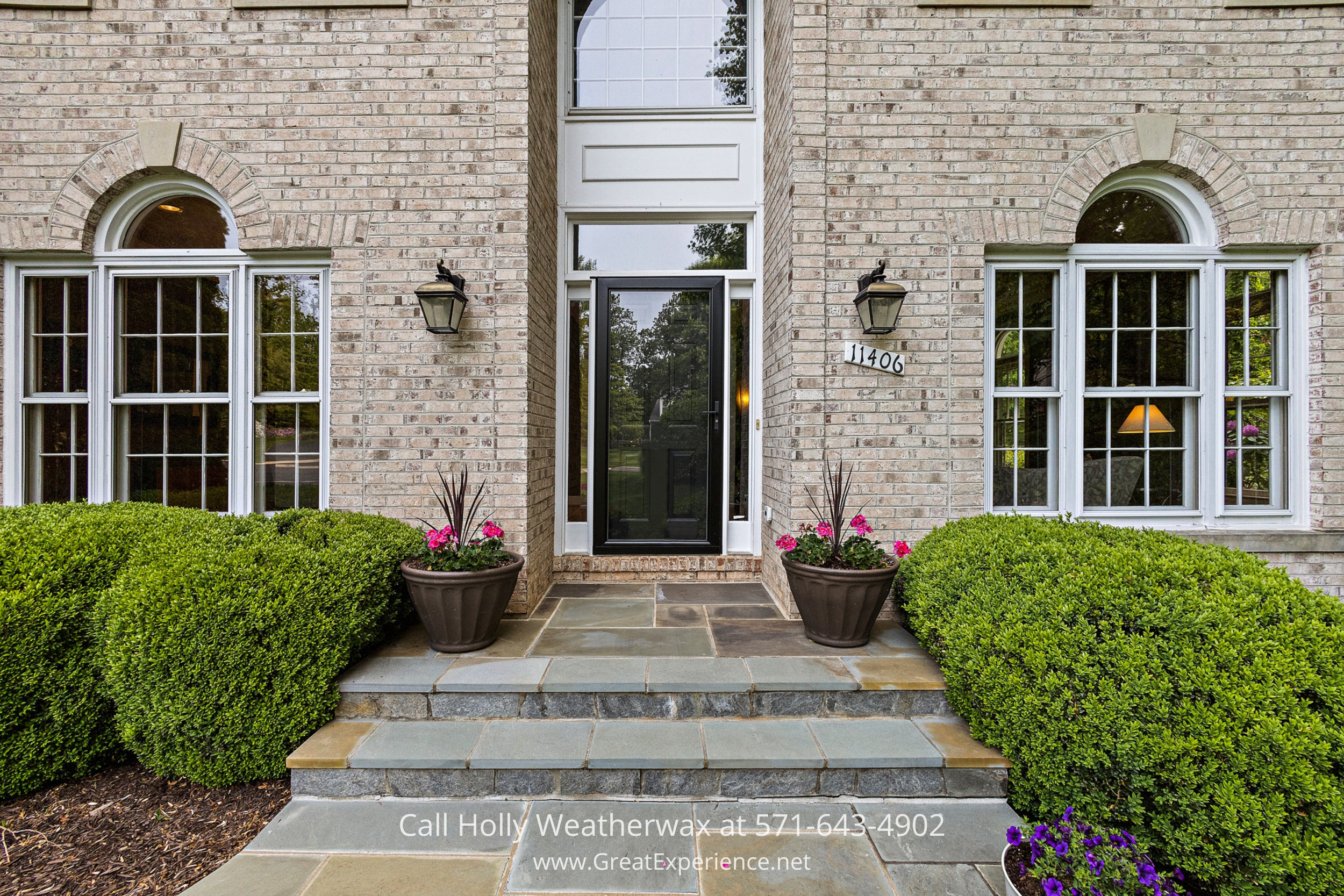 Charming brick house with a striking black door and decorative planters