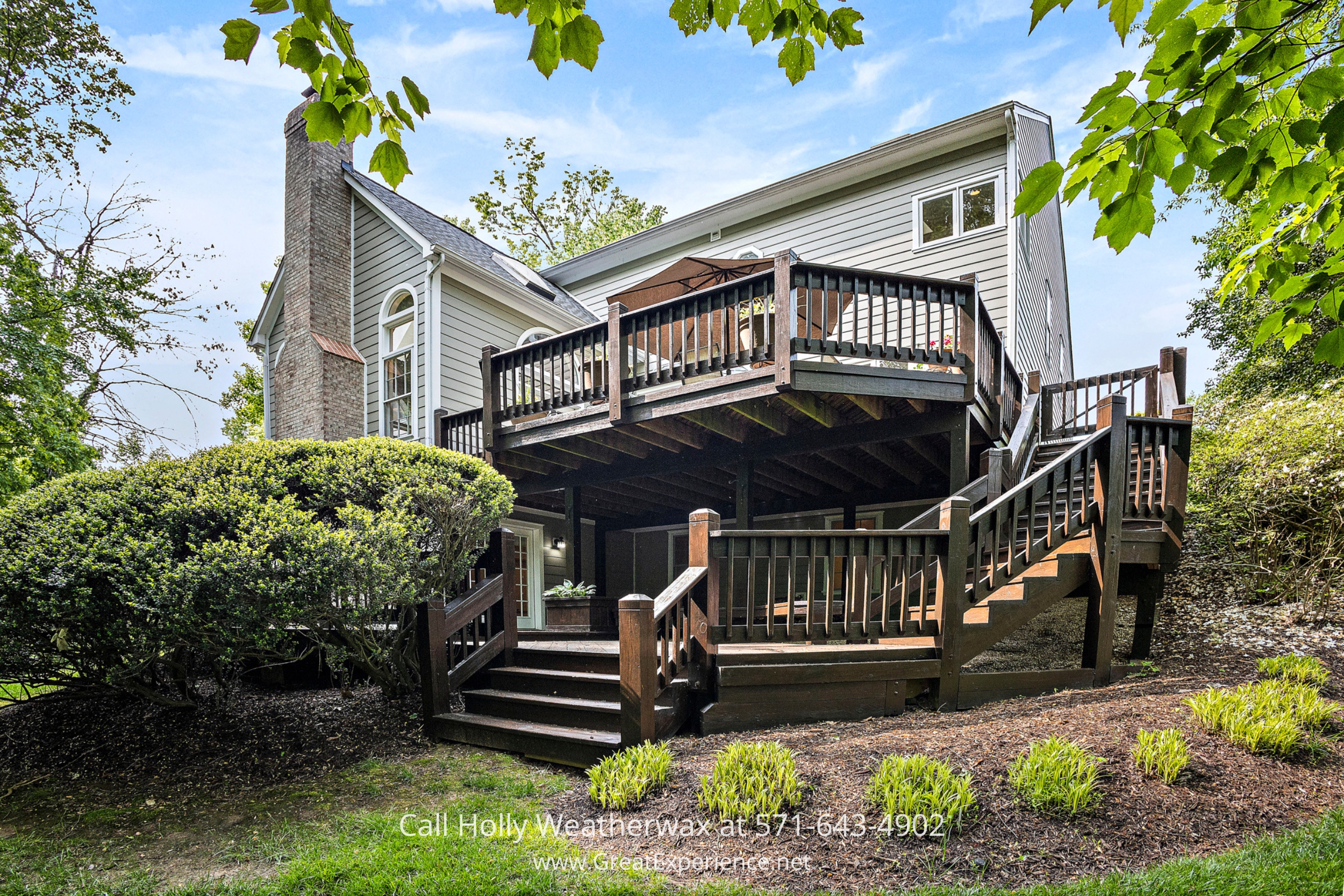 Grand house featuring a spacious deck and elegant stairs