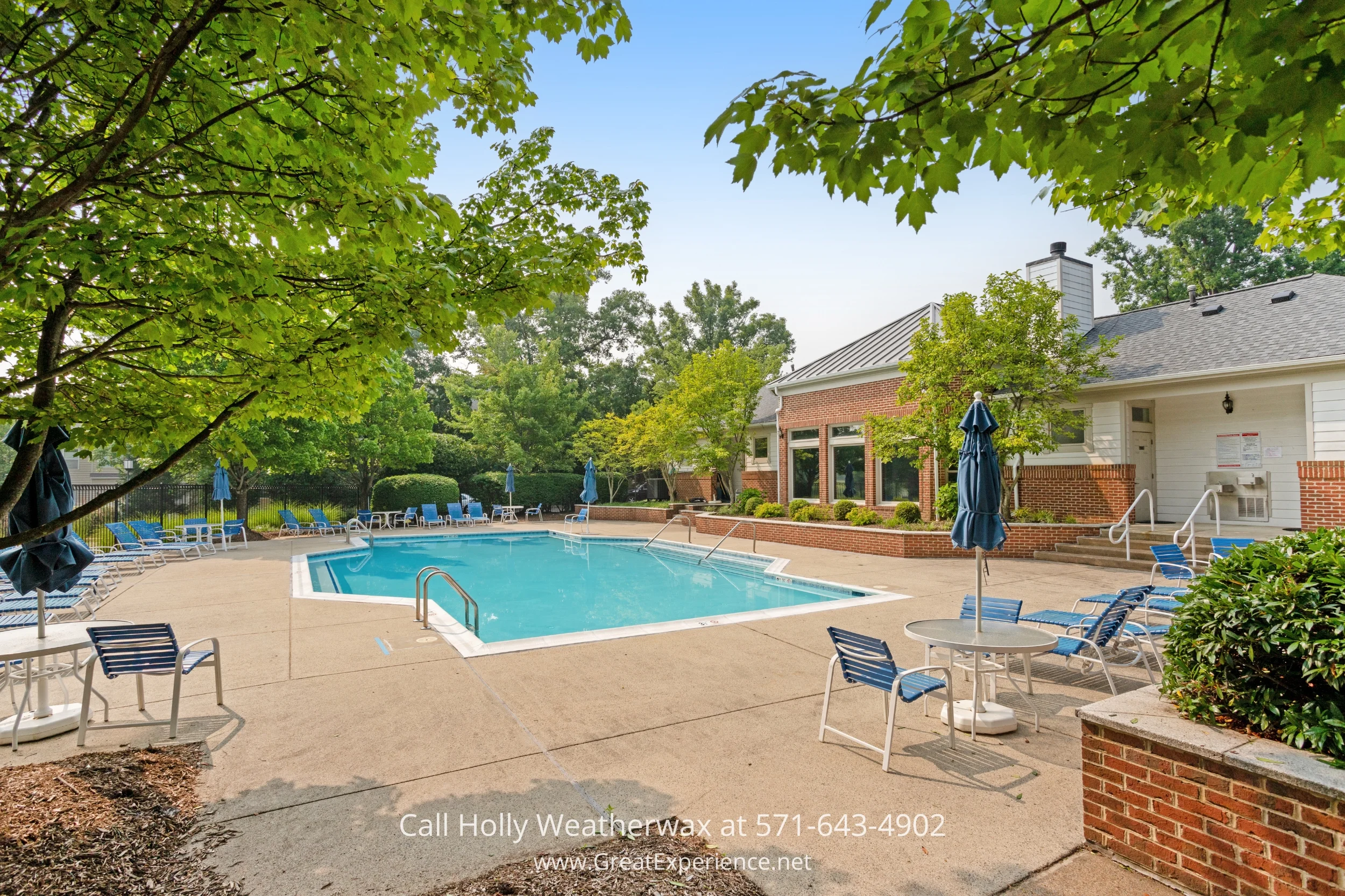 A refreshing swimming pool surrounded by lawn chairs, umbrellas, and trees in the background