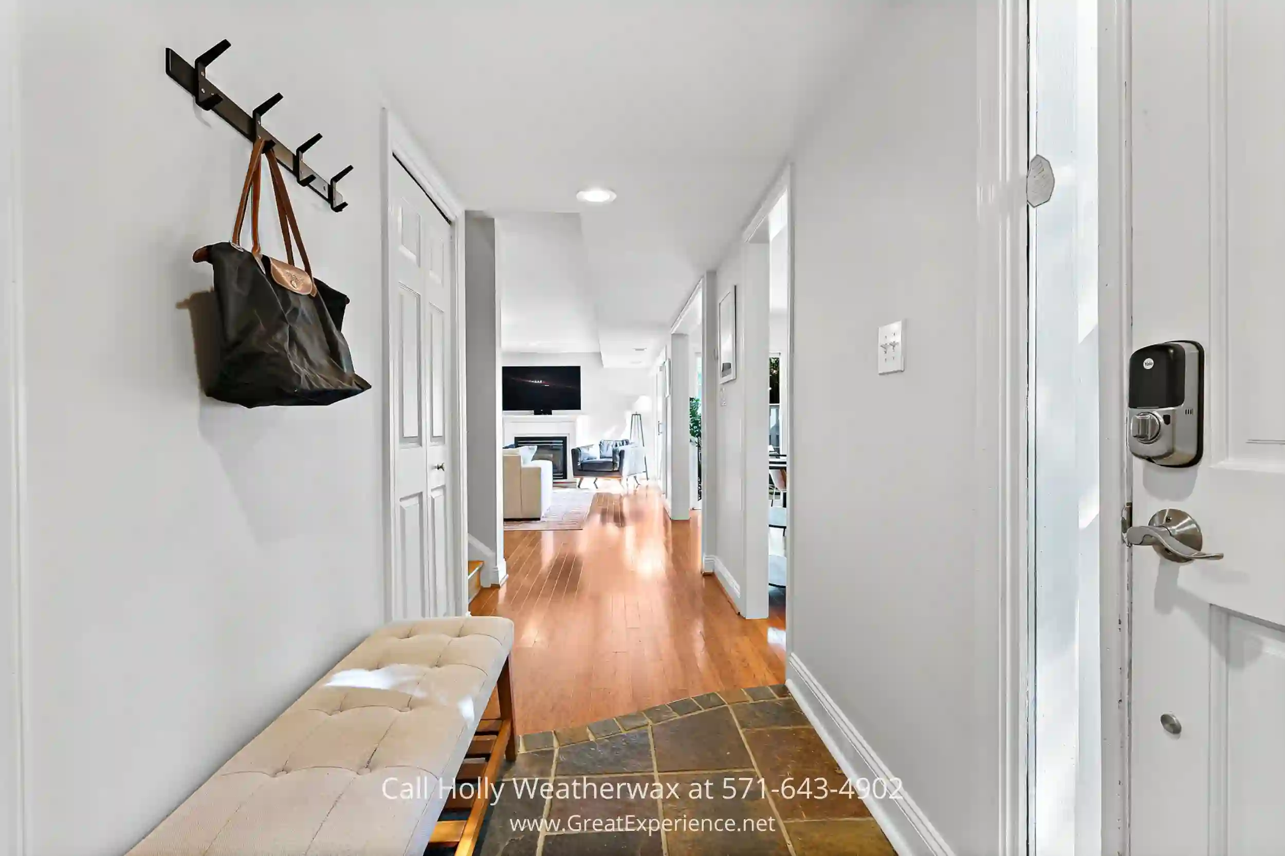 a long hallway with a bench and a coat rack with a bag hanging on it