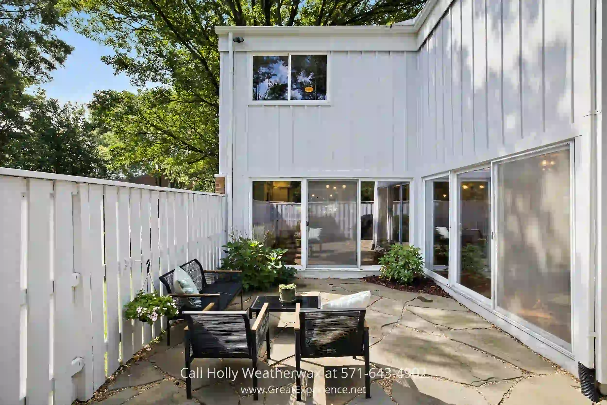 an outdoor courtyard with chairs and a table in front of a house