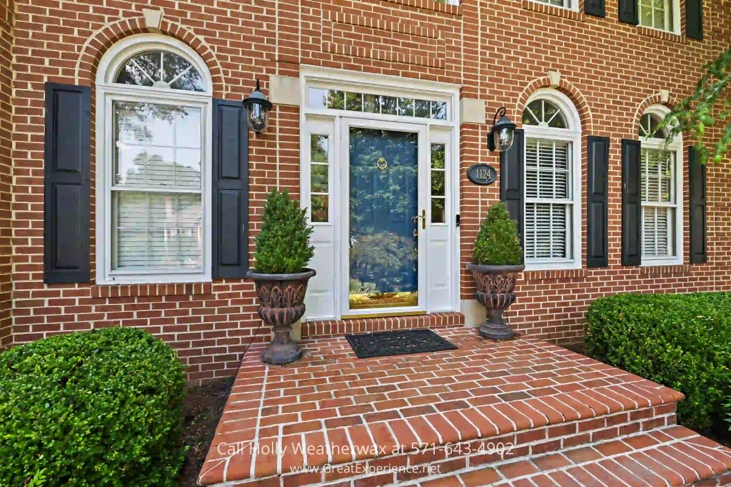 a brick house with two planters on the front steps