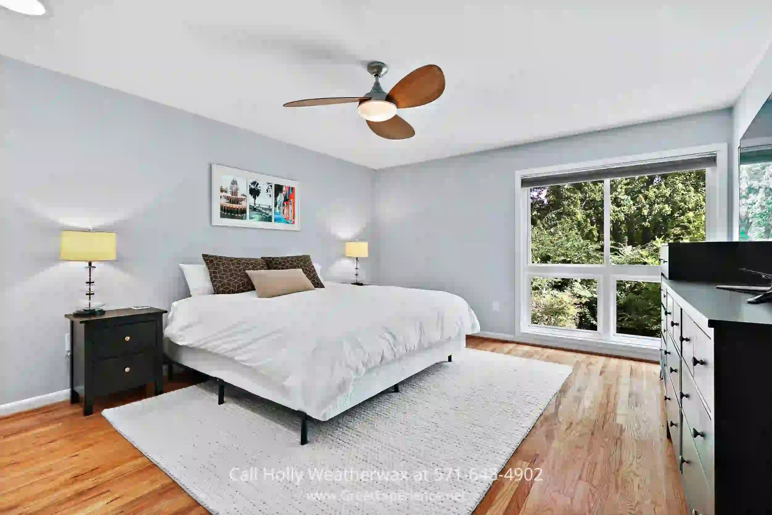 a bedroom with white walls, a bed and a ceiling fan