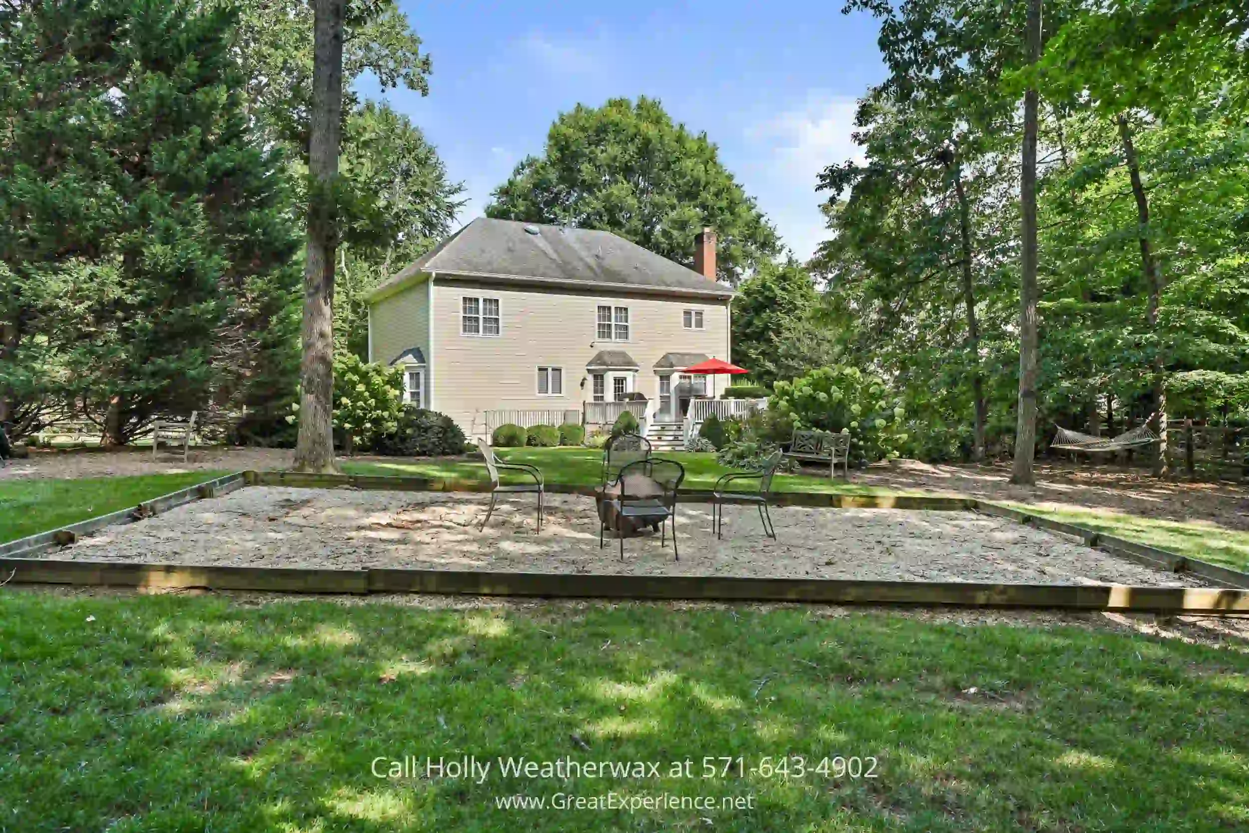 a house in the middle of a yard with a table and chairs