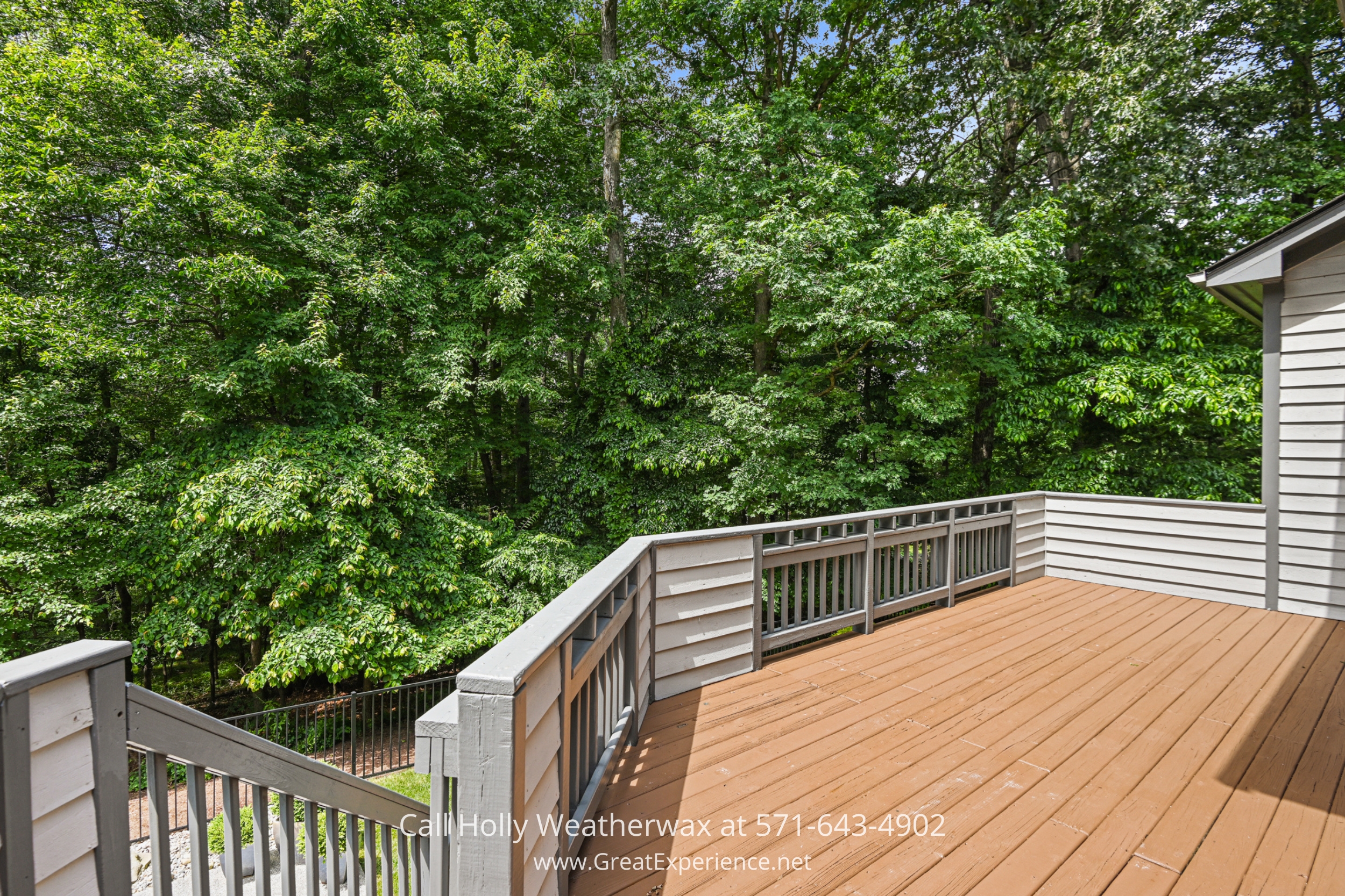 a wooden deck with a fence and trees in the background