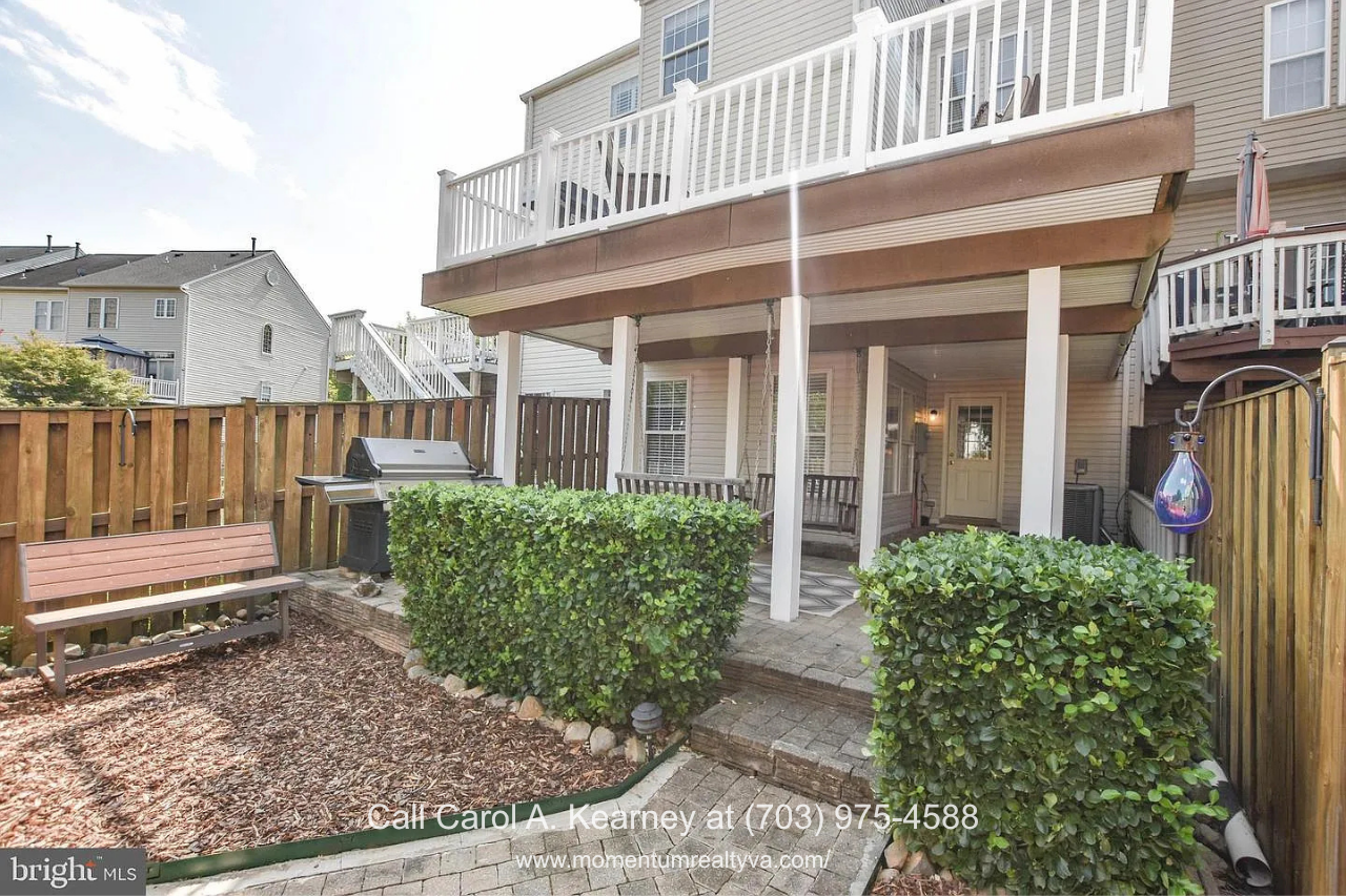 Backyard Patio and Deck – 25474 Brickell Dr Fenced backyard at 25474 Brickell Dr in South Riding, Chantilly, VA, featuring a covered patio, upper-level deck, landscaping, and outdoor seating area.