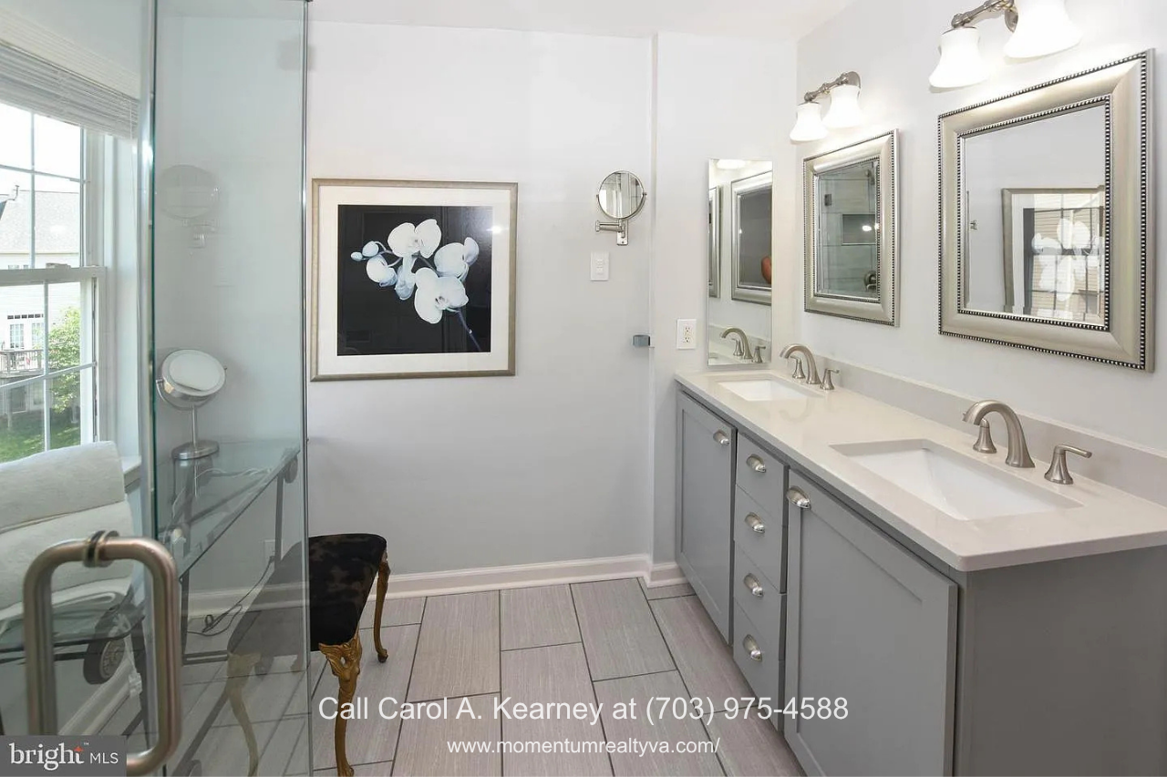 Primary Bathroom Double Vanity – 25474 Brickell Dr Primary bathroom at 25474 Brickell Dr in South Riding, Chantilly, VA, featuring a double-sink vanity, large mirrors, and a glass-enclosed shower.