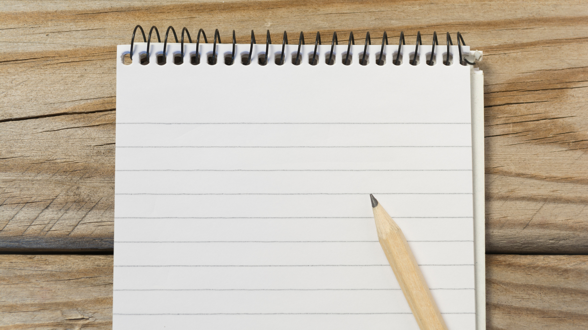 DIY Home Repairs Decision-Making Tool A wooden table holds a blank notebook and a pencil, perfect for planning DIY home repairs and decision-making.