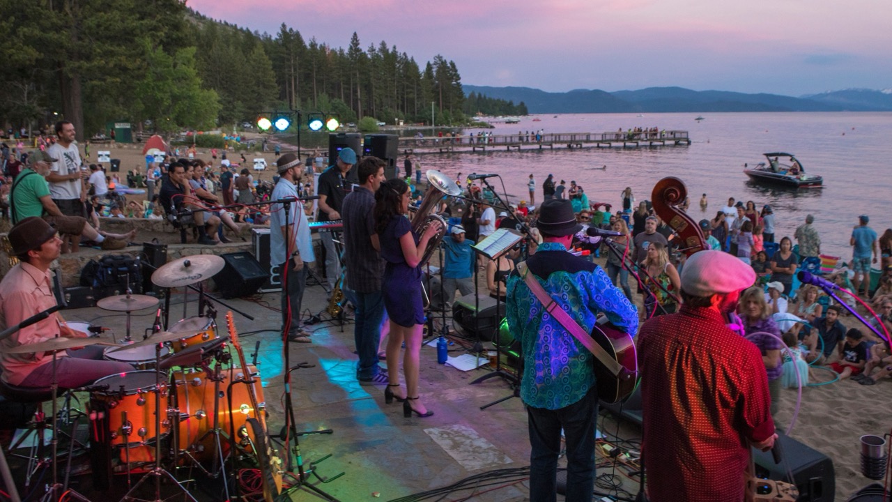  A group of people performing on stage at sunset during the Tahoe Music on the Beach event.