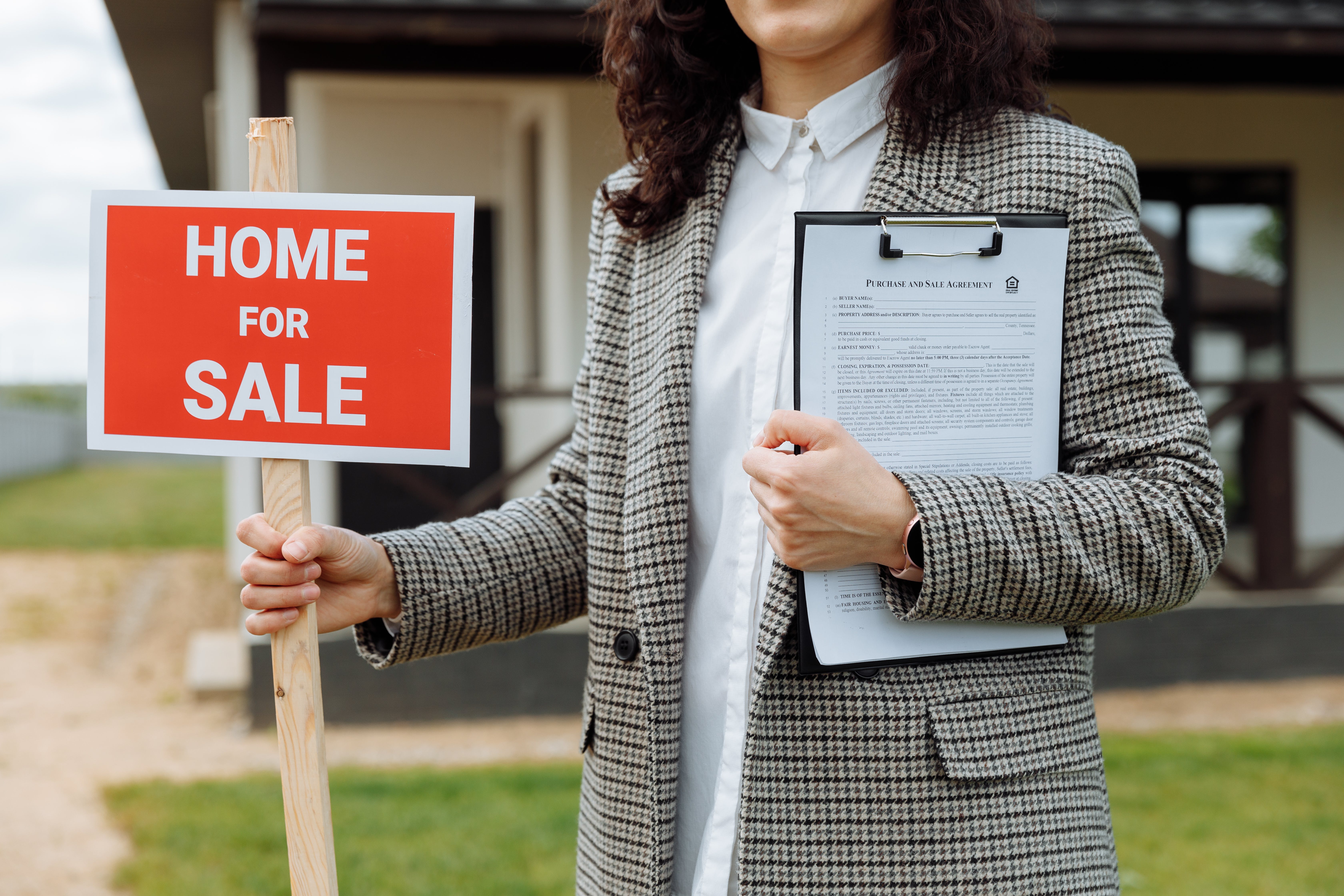 an agent holding a home for sale sign