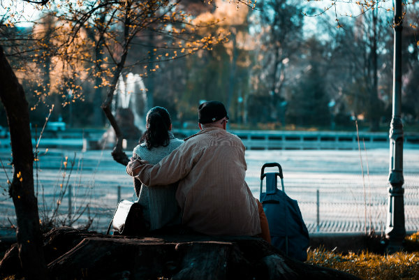 Father and daughter sitting next to each other on a bench in park