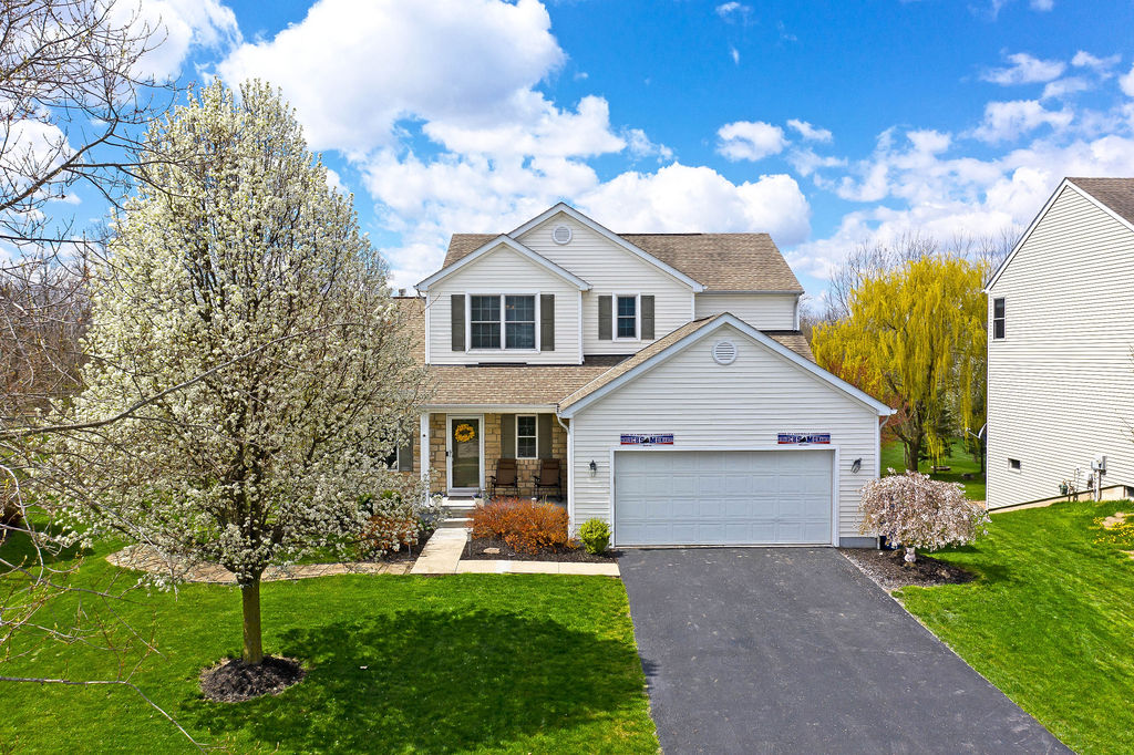 Two-story single-family home in Mill Valley, Marysville, Ohio, with attached two-car garage, blooming trees, and landscaped front yard.
