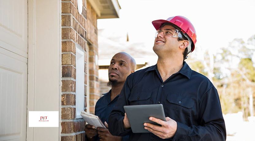 Home inspector in hard hat checking exterior of a house