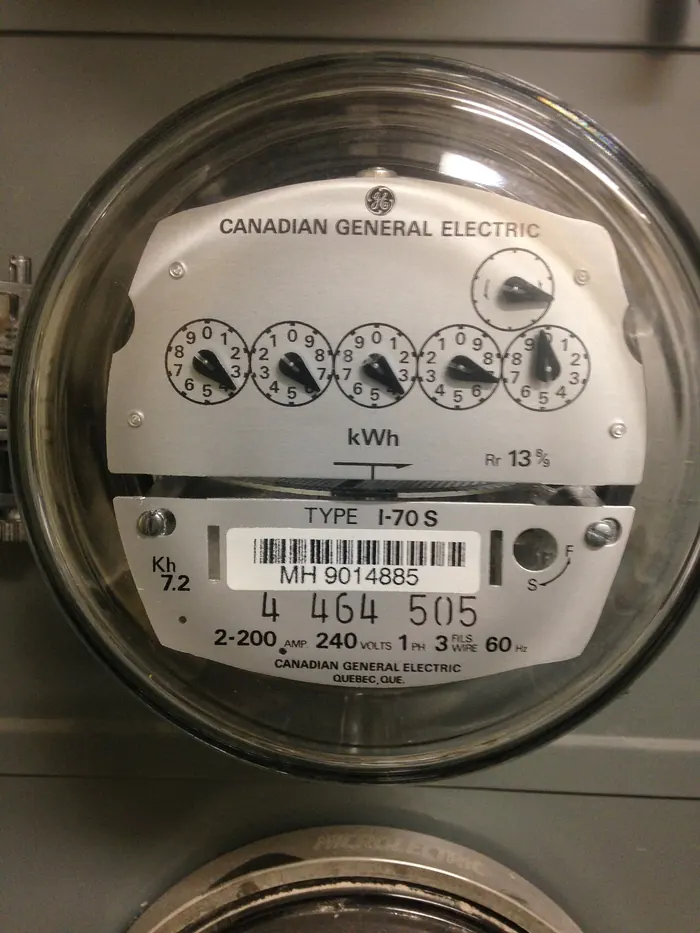 Close-up of an analog electric meter with dials in a residential apartment building