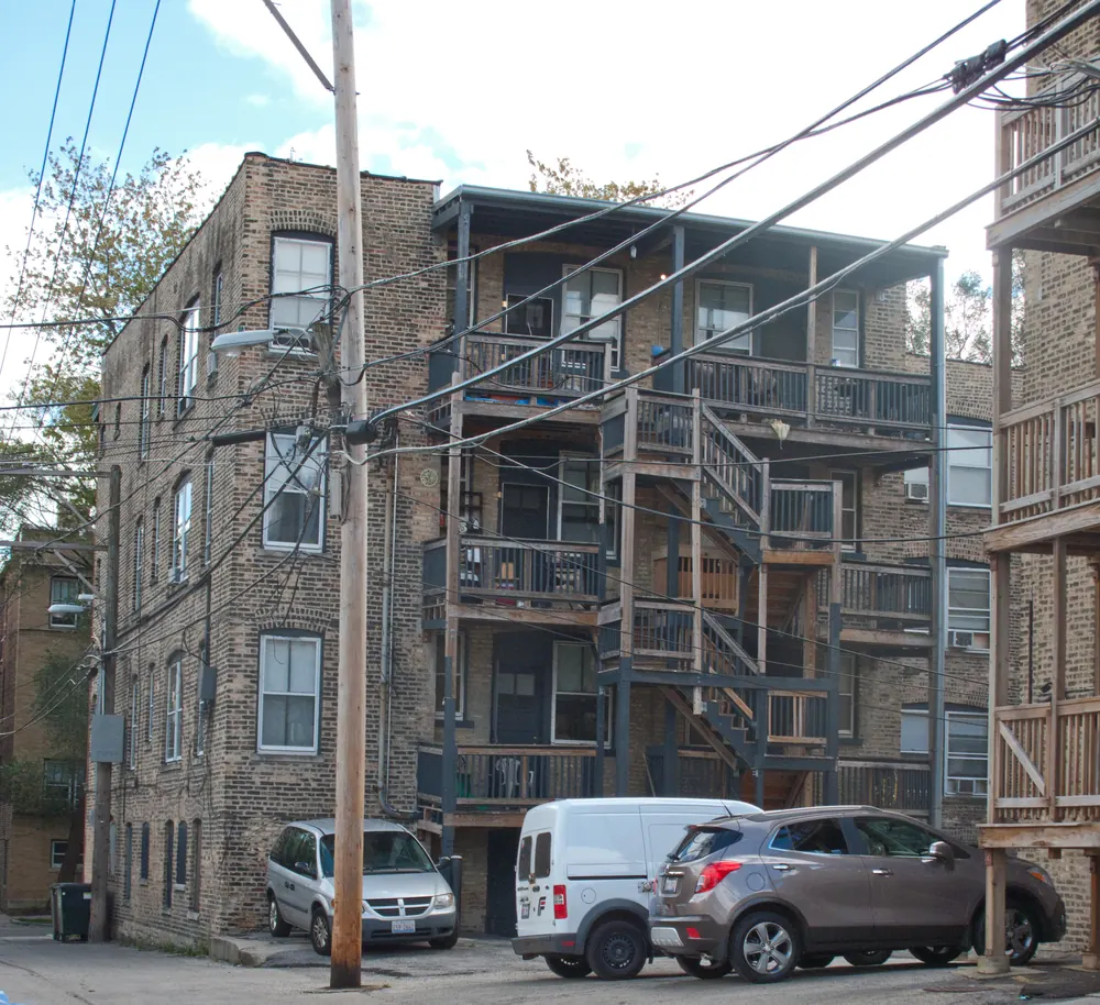 Stacked wooden back porches and stairs on the rear of a vintage brick apartment building in Rogers Park, Chicago