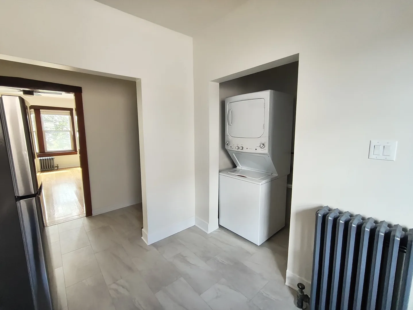 Stacked in-unit washer and dryer in an alcove off the kitchen of a W Albion Ave apartment