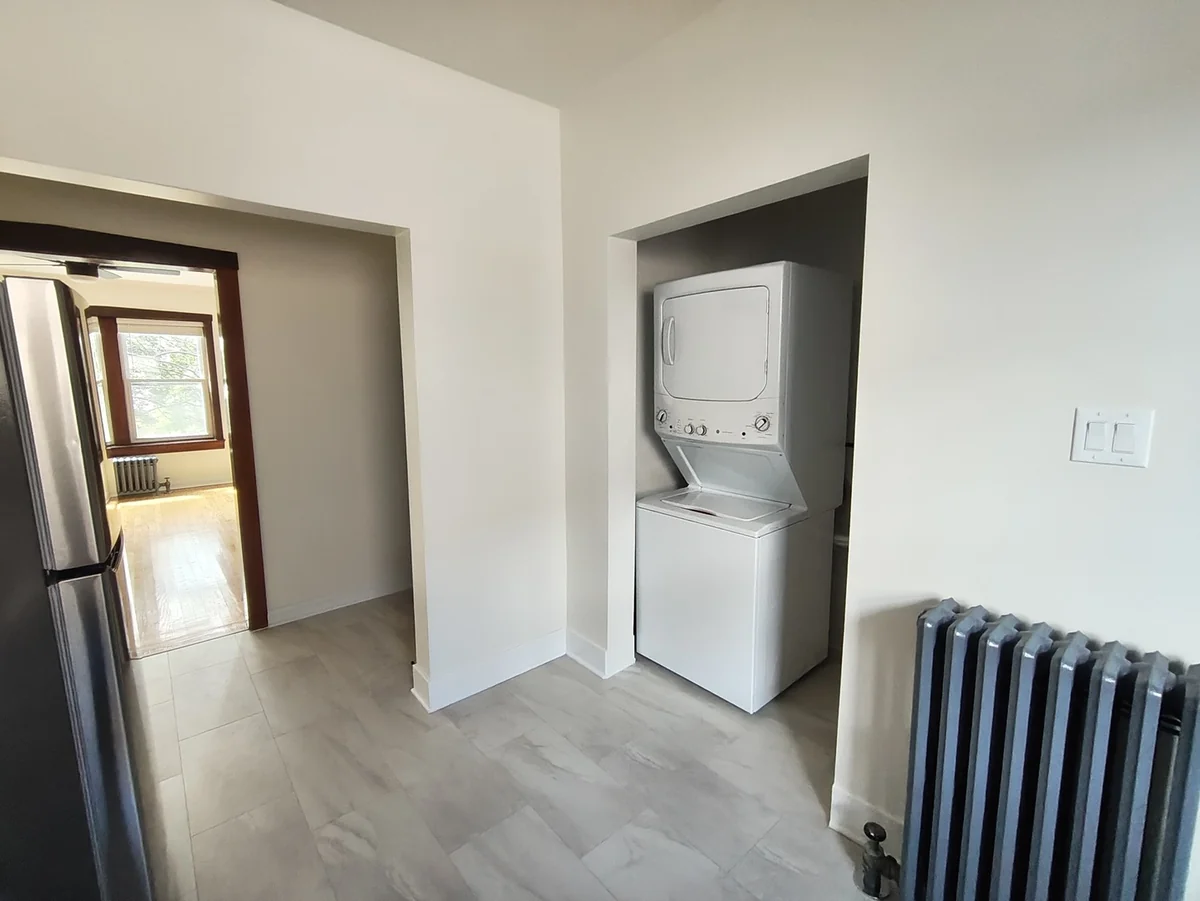 Stacked in-unit washer and dryer in a closet next to the kitchen of a W Albion Ave apartment
