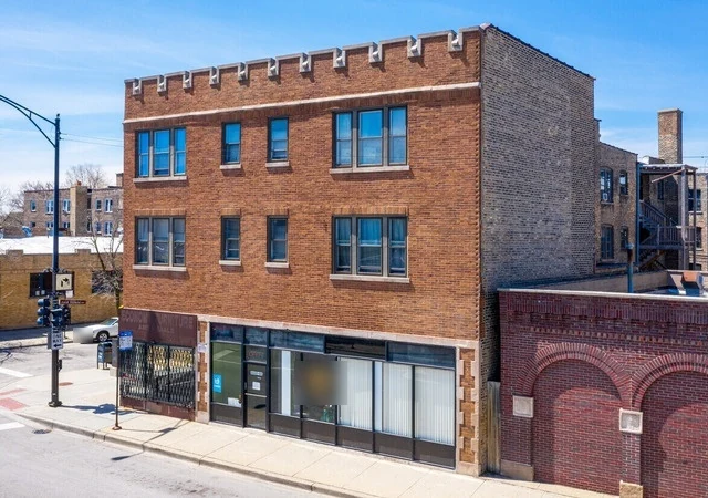 Brick building with a row of glass storefront windows at 6602 N Clark St in Rogers Park, Chicago