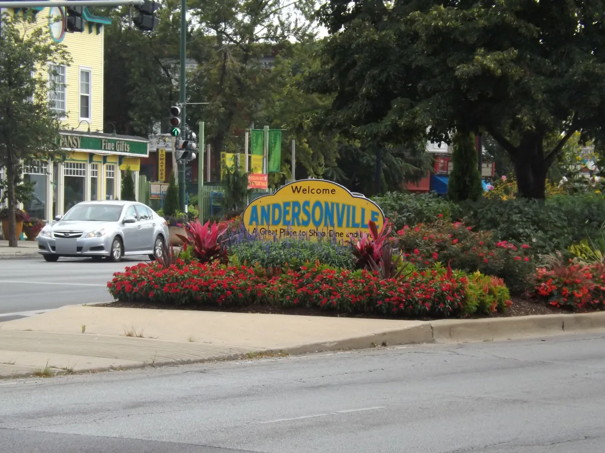 Yellow Welcome to Andersonville sign in a flower bed where Clark Street and Ashland Avenue split in Chicago