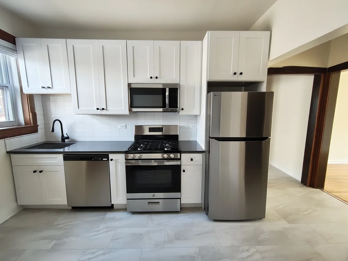Renovated kitchen with white shaker cabinets, dark counters and stainless steel appliances on W Albion Ave