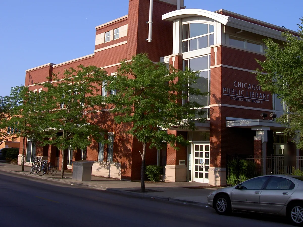Red-brick Chicago Public Library Rogers Park Branch building with street trees on N Clark St
