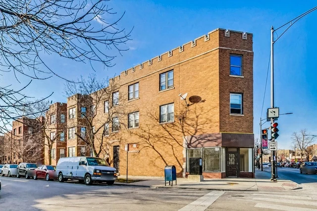 1927 brick corner building with ground-floor storefronts at Clark St and Albion Ave in Rogers Park, Chicago