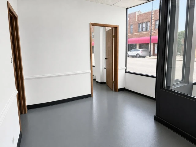 Bright office room with a tall storefront window and doorways to other rooms at 6602 N Clark St
