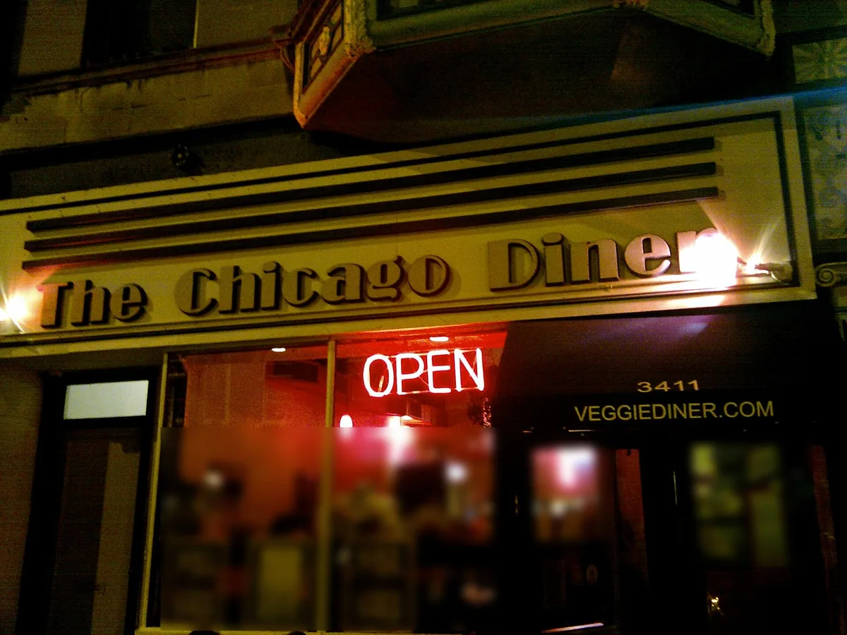 Lit sign and storefront of The Chicago Diner at 3411 N Halsted St in Lakeview East, Chicago, at night
