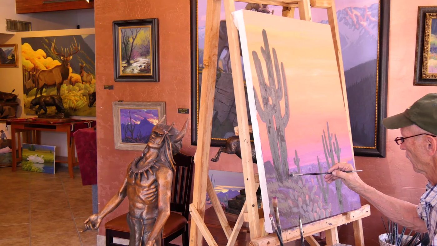 Artist painting a saguaro landscape in a Carefree gallery studio