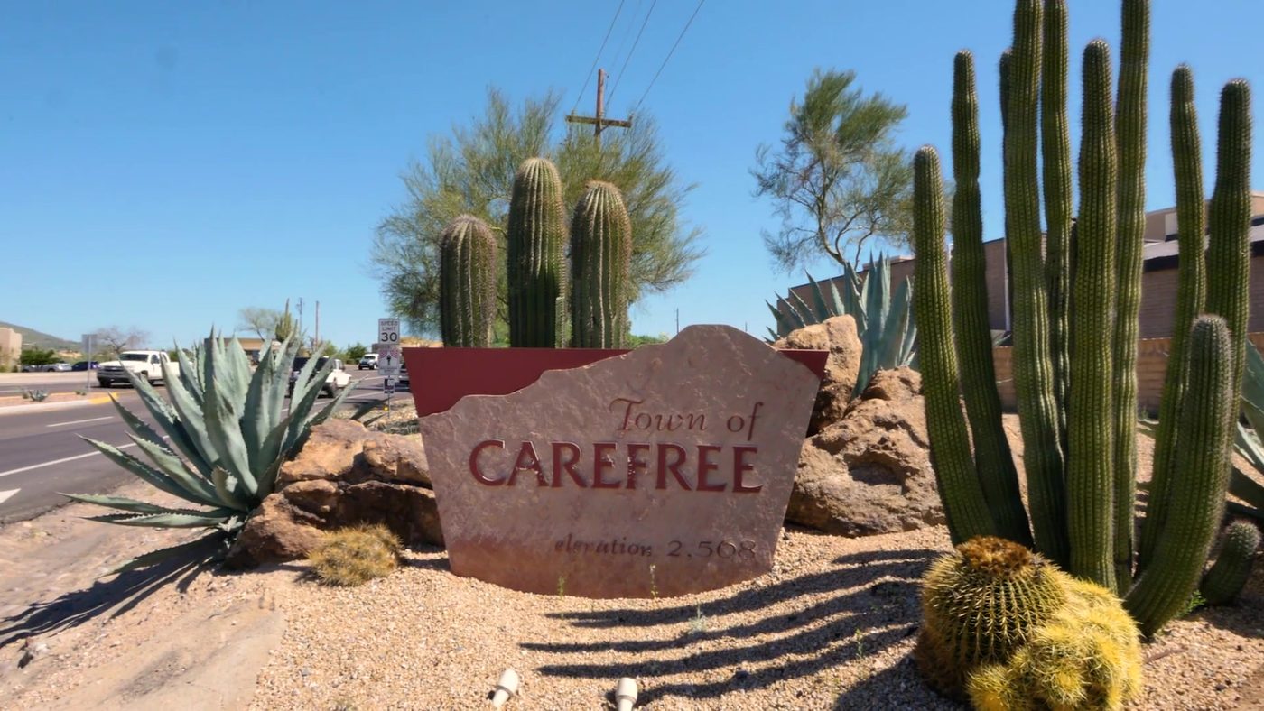 Town of Carefree stone sign among saguaro and barrel cactus