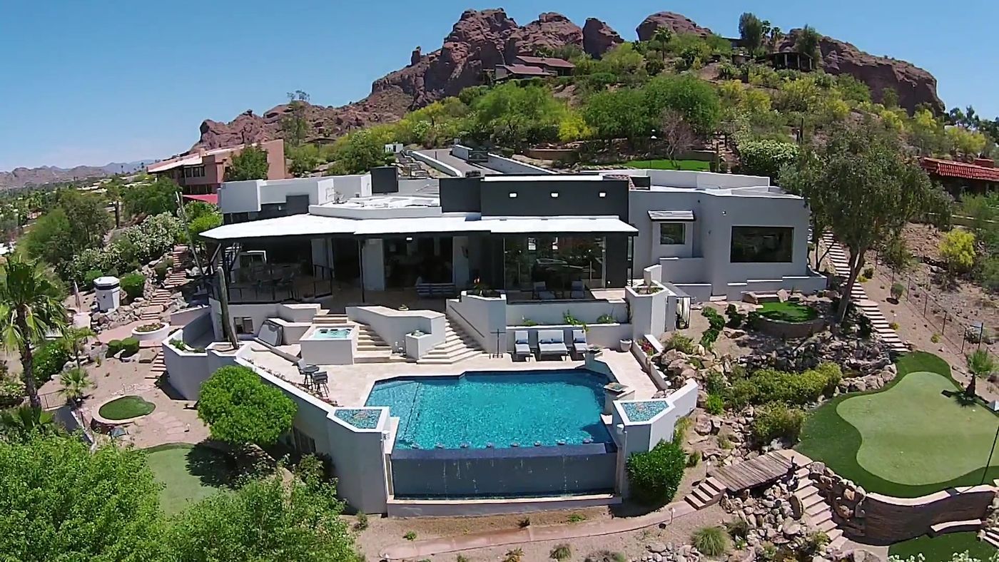 Aerial view of a modern Scottsdale estate with an infinity pool and putting green