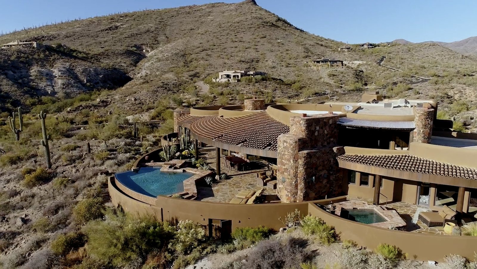 Hillside estate with an infinity pool and clay-tile roofs among saguaros in Desert Mountain