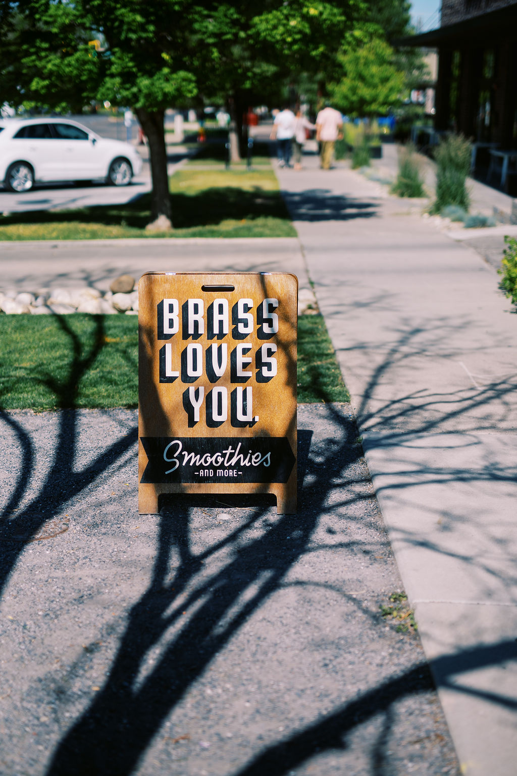 a wooden a frame sign reads Brass Loves You: Smoothies and More