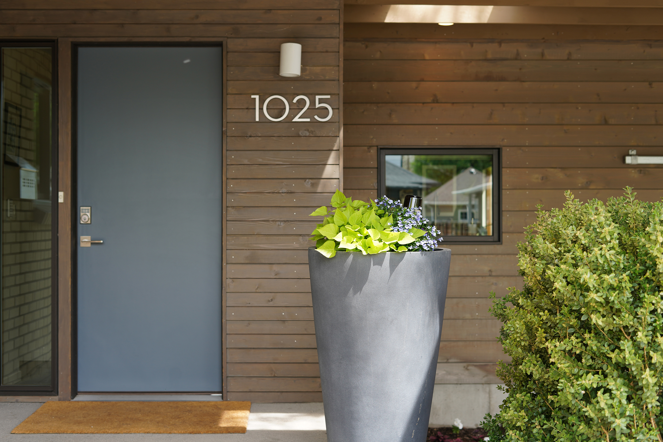 a modern doorway with 1025 door numbers and a cement planter in front