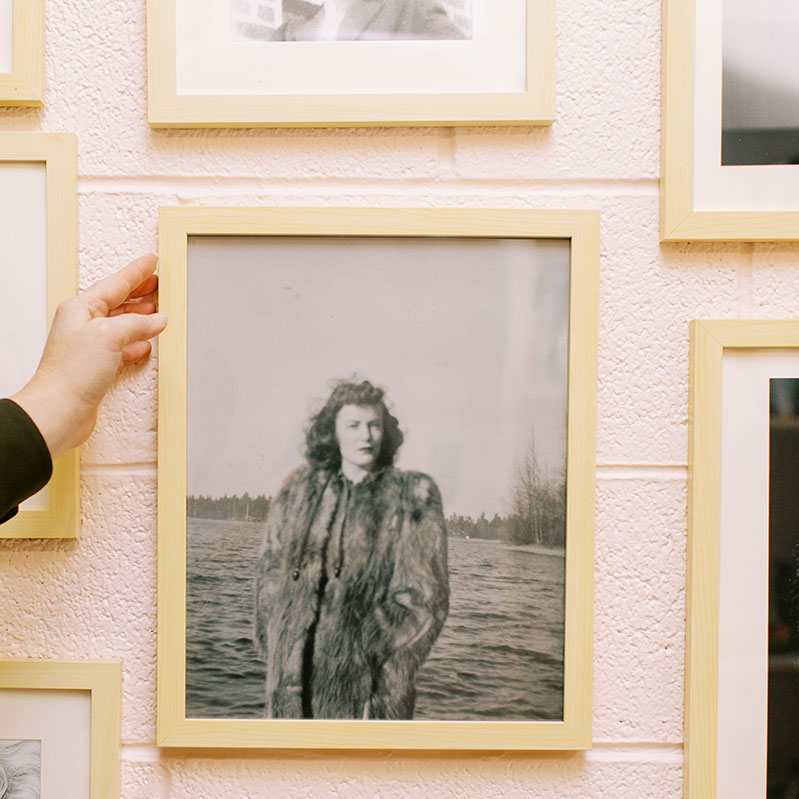 a woman hangs a black and white photo of a woman in a fur coat