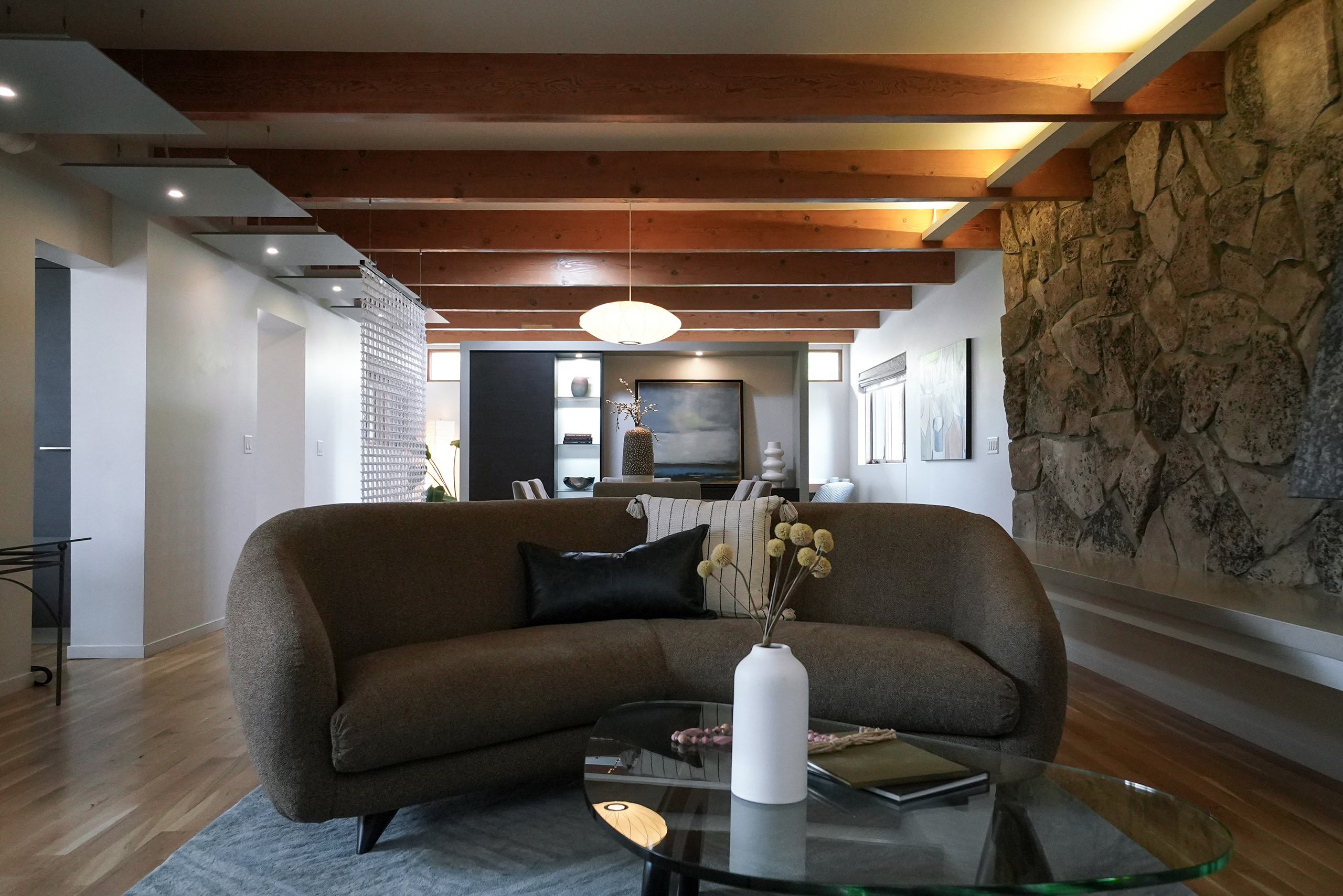 a brown modern couch in a mid century modern interior with exposed beams