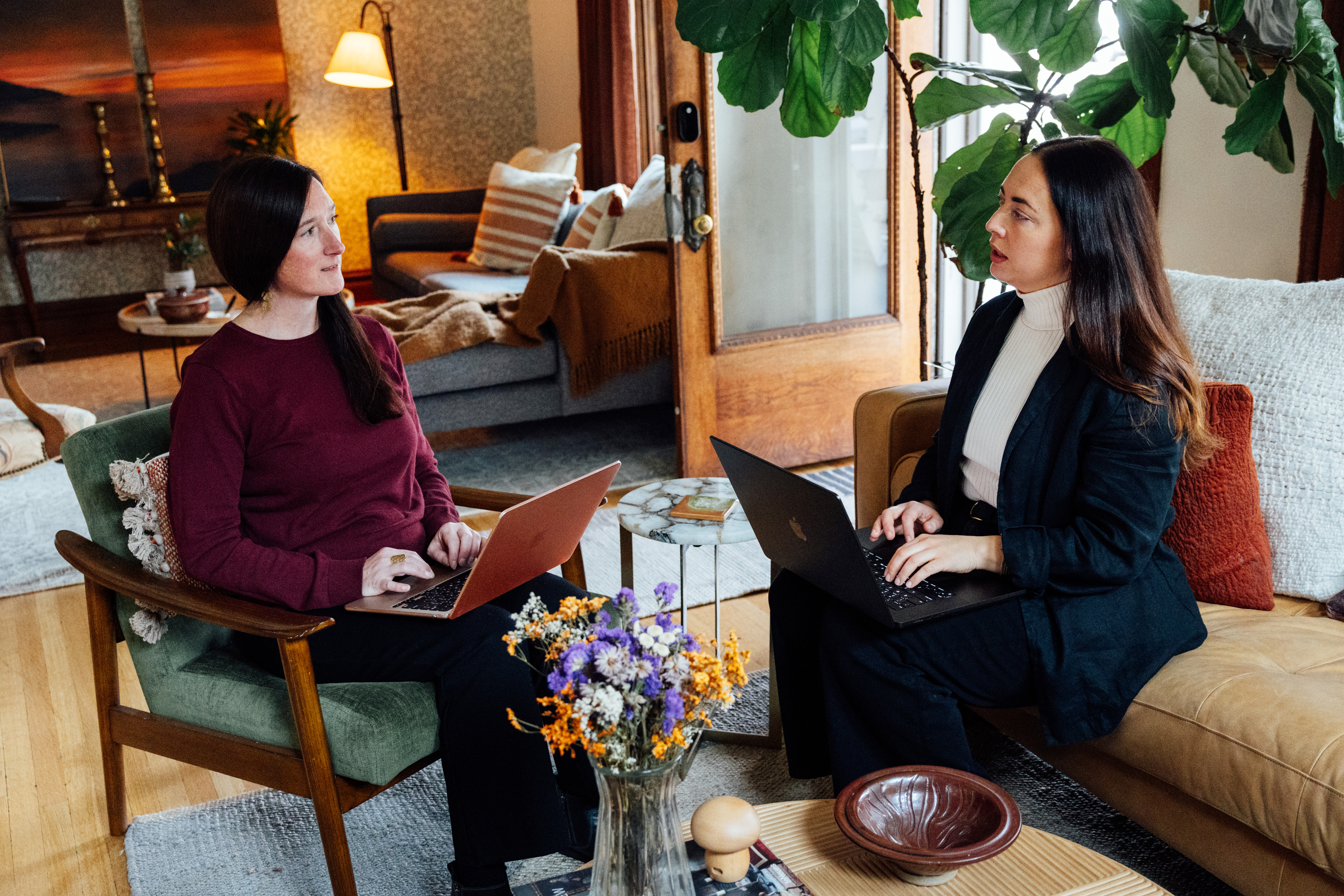 Monique Higginson and Jenni Holmstead meeting to discuss over laptops in a living room