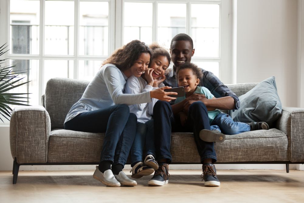 a family sitting on the couch watching a virtual tour on the phone